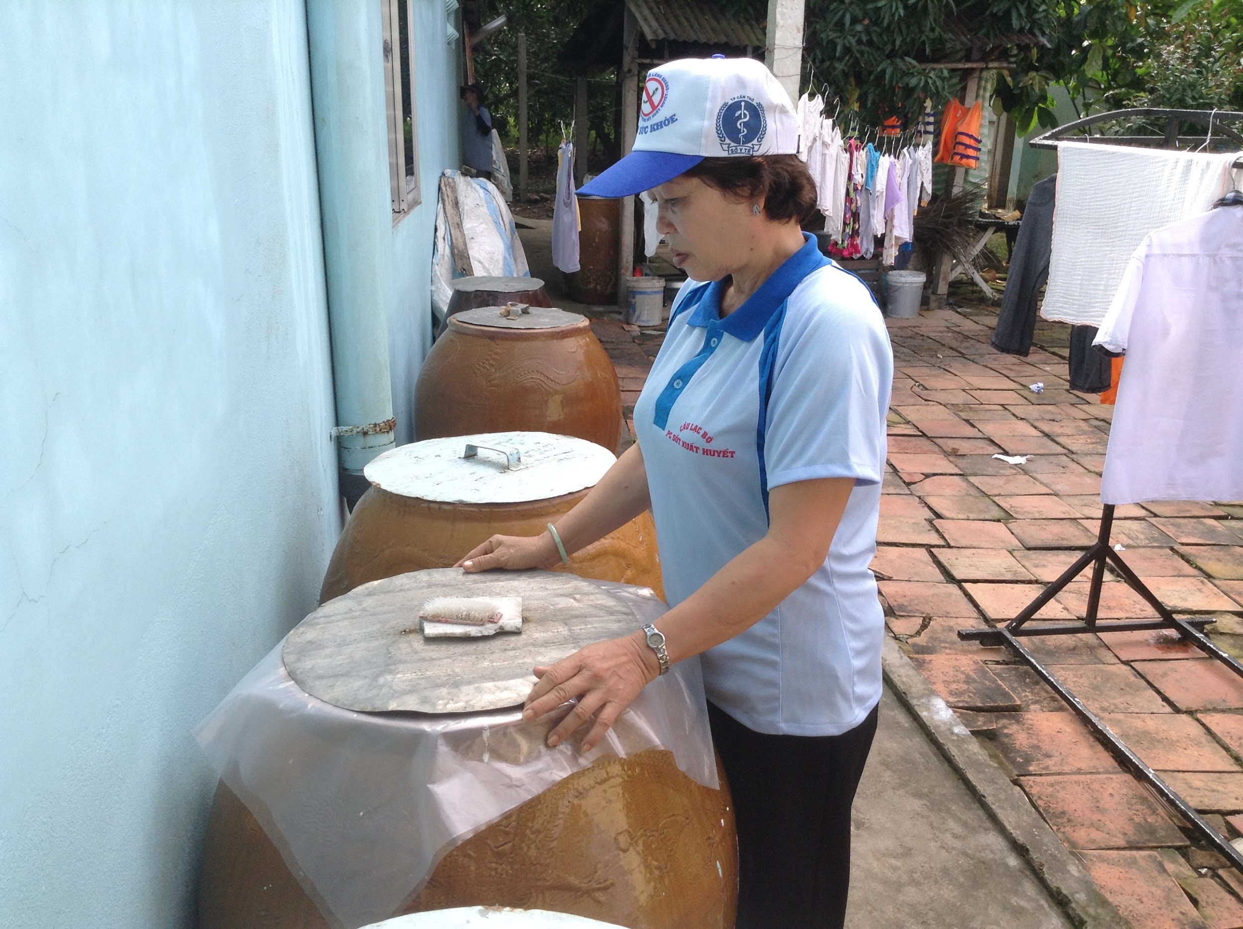 Health club members encourage plastic sheeting over water storage tanks to prevent mosquitoes from breeding. (Photo courtesy of Nguyen Van Viet/Can Tho Preventive Health Centre)