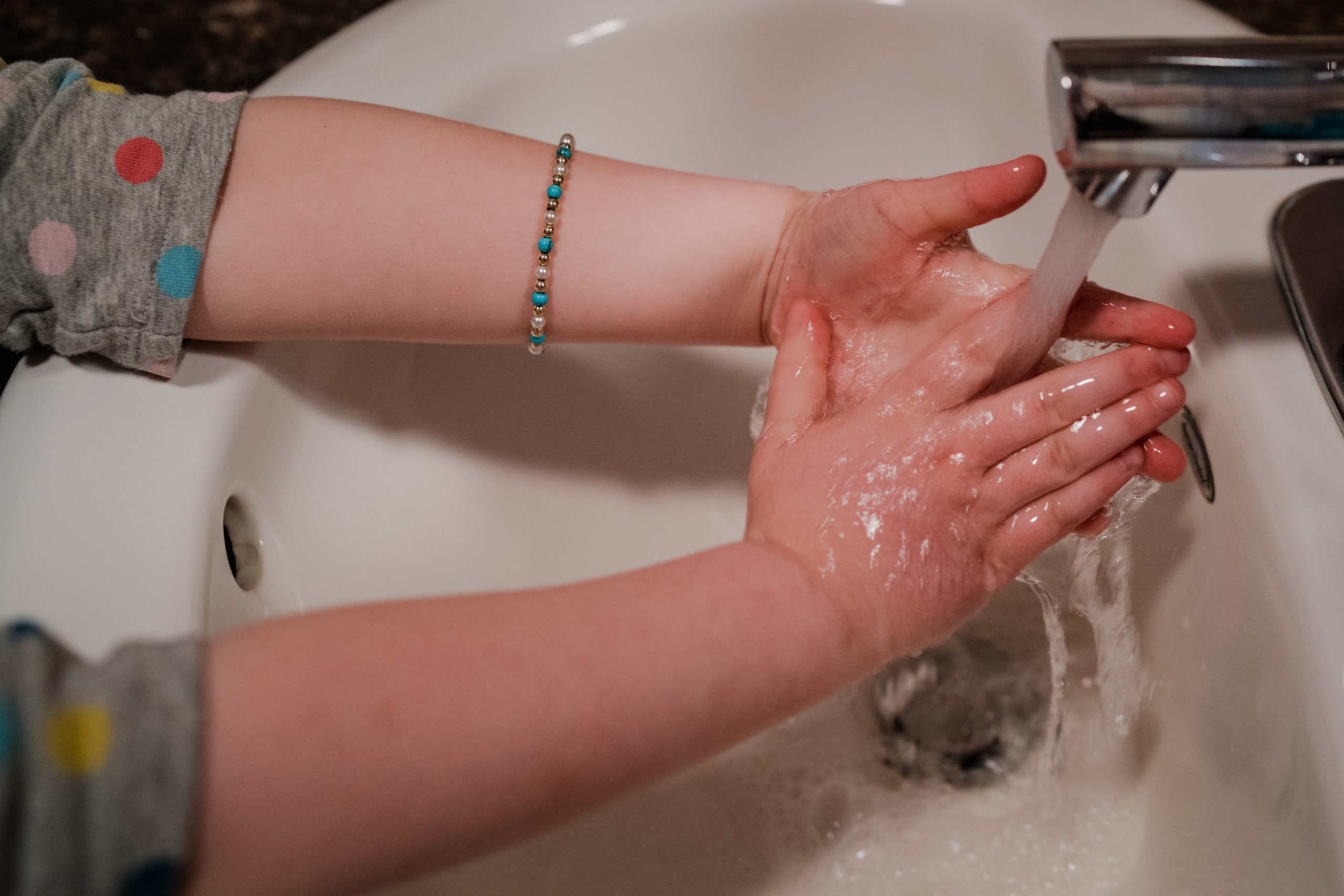 Child washing their hands at a bathroom sink.
