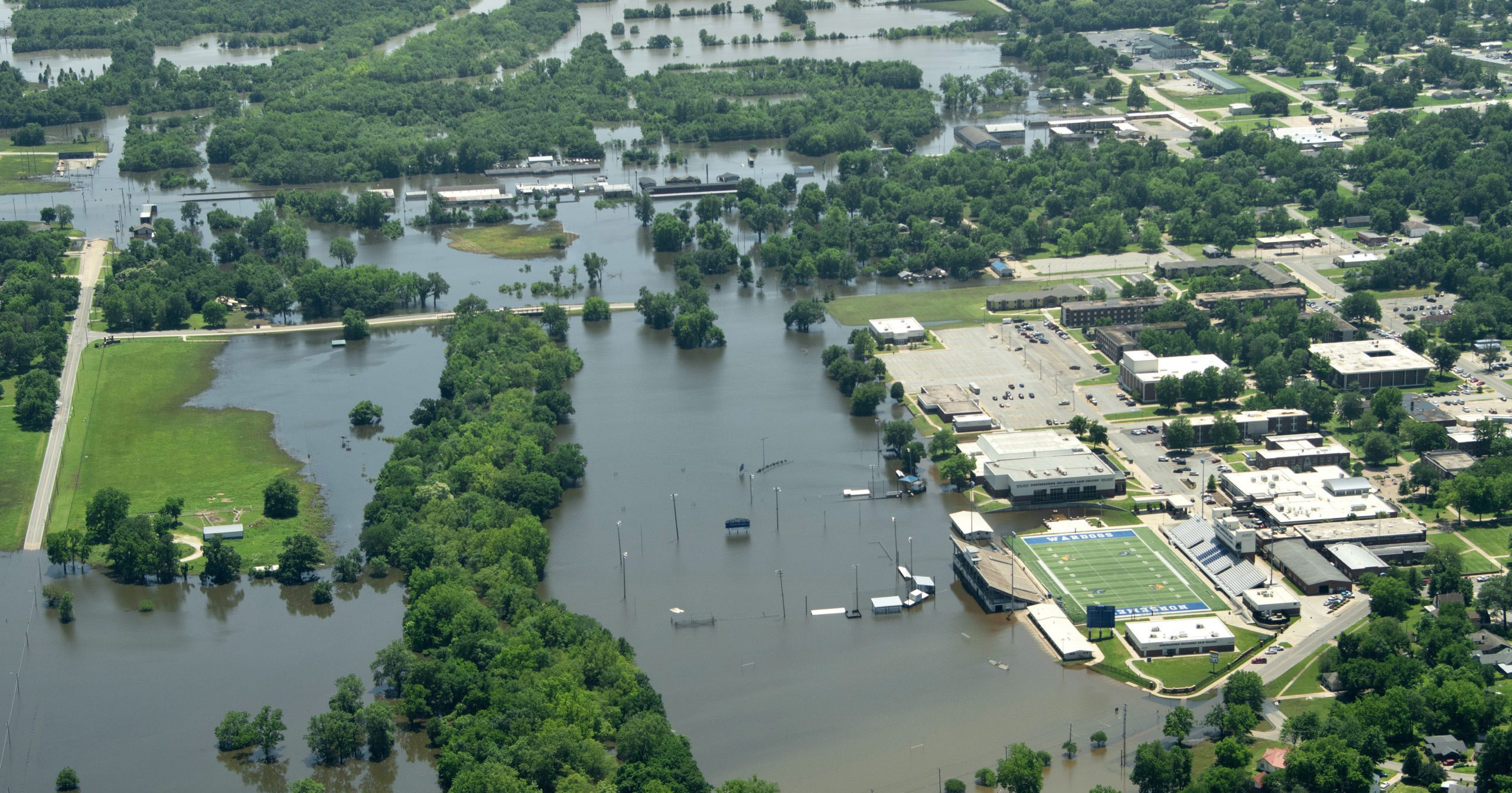 An aerial view of a flooded community. Rooftops and treets peek above high waters in Ottowa County, OK