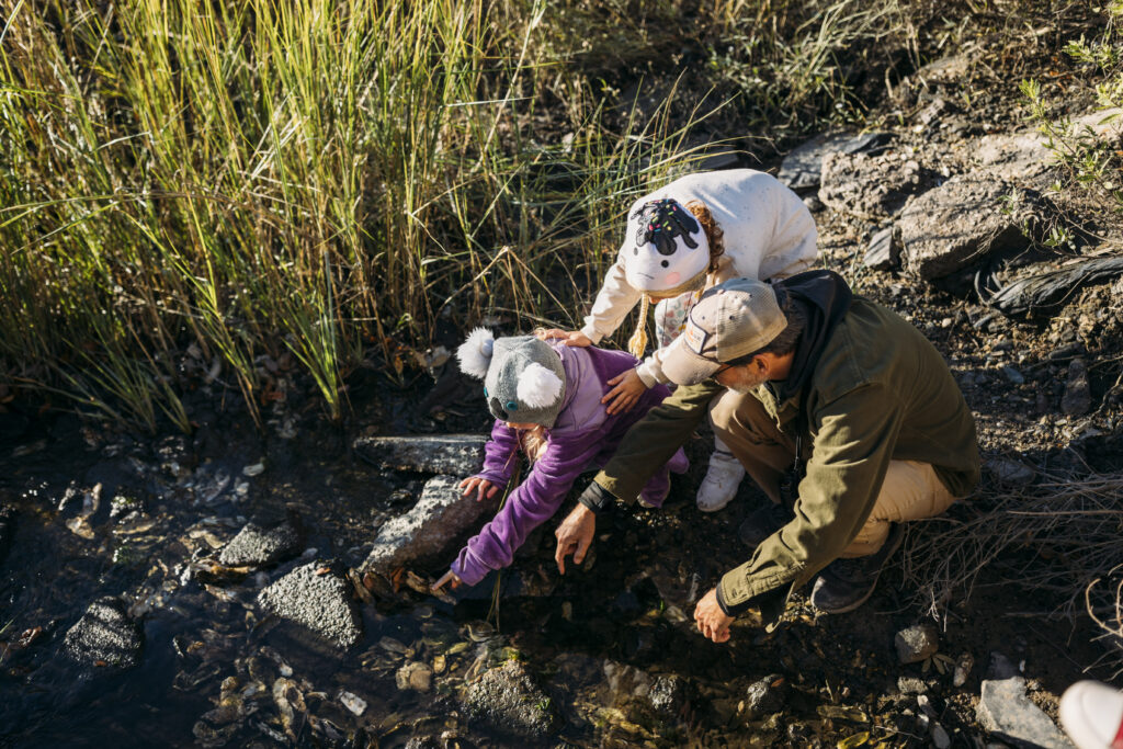 a family examines a river shoreline