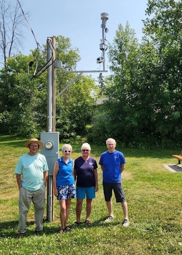 Project team standing outside near an air monitor